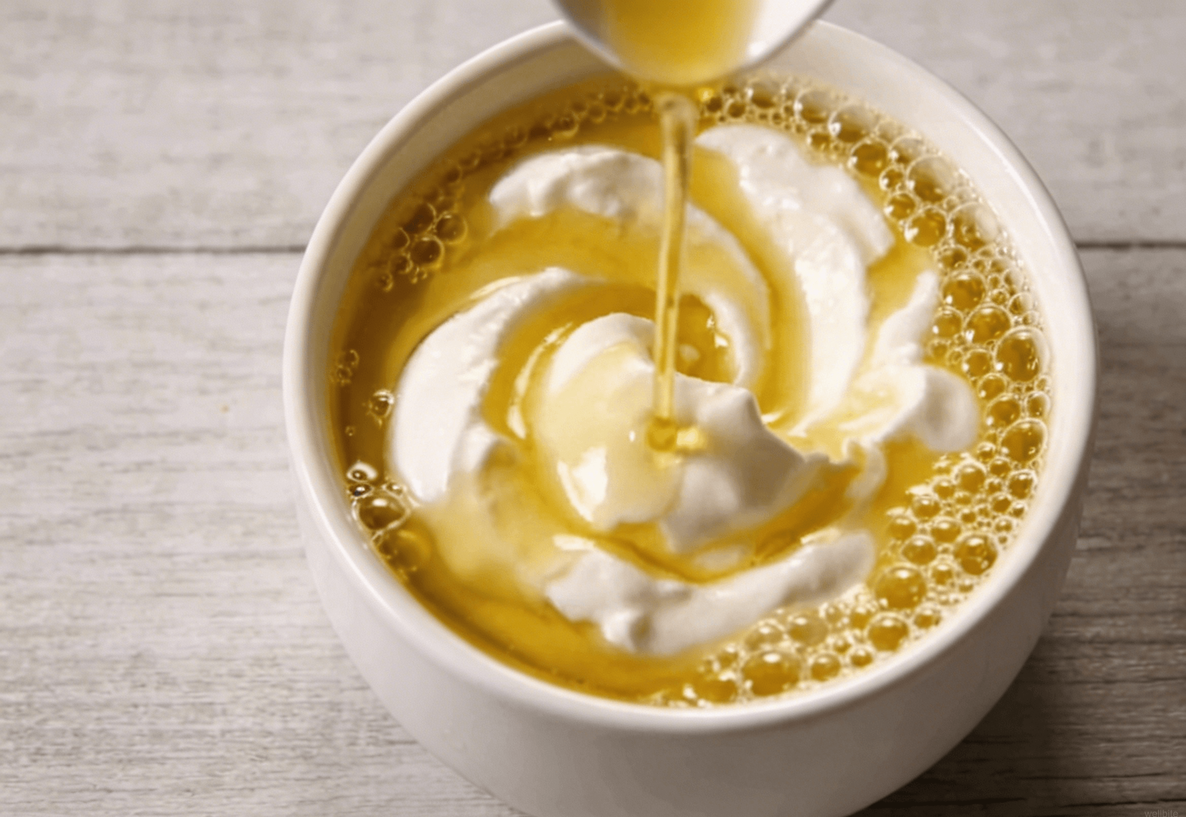 Greek yogurt, olive oil, and lemon juice being whisked together in a small bowl